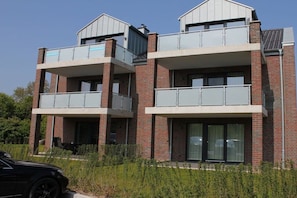 A modern two-story residential building with balconies and large windows. - Herring Gull in the Cherry Orchard 1 (Kellenhusen)