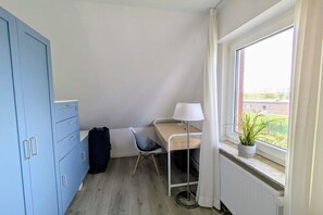 A small room with a desk, chair, lamp, and a window with a view of the outside. - Holiday home in Borkum with swimming pool (Borkum)