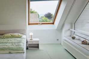Une chambre avec un puits de lumière, un lit, une table de chevet avec une lampe et un radiateur.