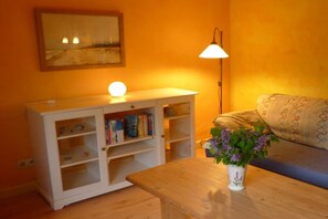 A room with a white cabinet, a table with a vase of flowers, a lamp, and a patterned sofa. - Baltic Sea House Sea Wonders (Born)