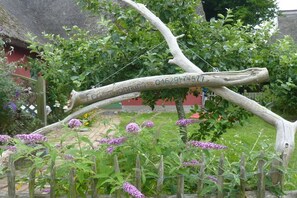 A wooden archway with a plaque, surrounded by greenery and flowers. - Baltic Sea House Sea Wonders (Born)