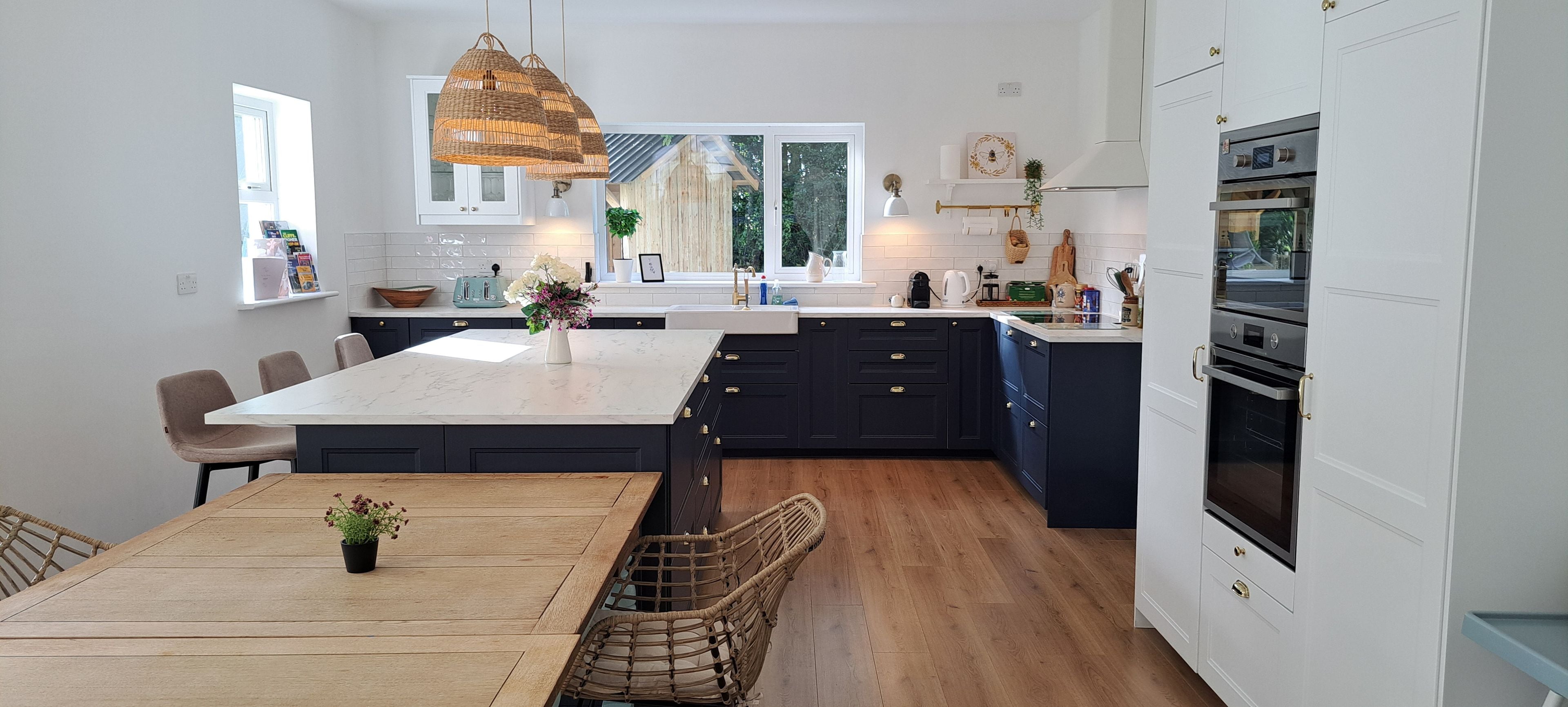 Una cocina moderna con una isla central, armarios oscuros y un horno empotrado.