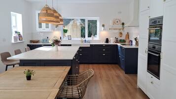Una cocina moderna con una isla central, armarios oscuros y un horno empotrado.