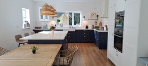 A modern kitchen with a central island, dark cabinetry, and a built-in oven.