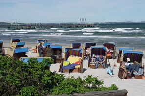Beach chairs with blue canopies and a view of the sea and a pier in the background. - Holiday apartment with 2 bedrooms (Scharbeutz)