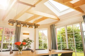 Ein Essbereich mit einem Holztisch, Stühlen, einer Blumenvase und einem Oberlicht.