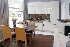 Eine moderne Küche mit weißen Schränken, einem Esstisch mit Stühlen und einer Kaffeemaschine.