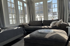Ein Zimmer mit großem Fenster, einer Couch, einem Bett und einem kleinen Tisch.