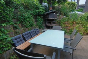 An outdoor patio with a table and chairs, surrounded by greenery. - Holiday home in Remagen with barbecue (Remagen)