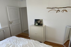 Ein Schlafzimmer mit einem Bett, einem weißen Kleiderschrank, einer Tür und einem Spiegel.