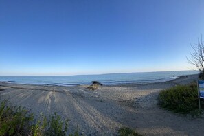 Ein Strand mit blauem Himmel, felsigem Ufer und einem Schild.