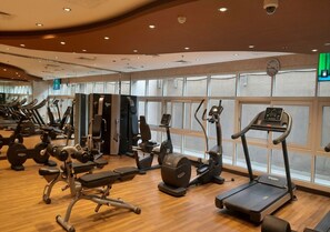 Ein Fitnessstudio mit unterschiedlichen Trainingsgeräten, großen Fenstern und Holzboden.