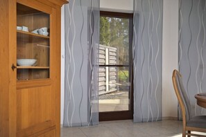 Ein Zimmer mit einem Holzschrank, einem Stuhl und einer Tür zu einem Außenbereich.