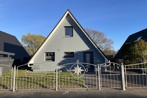 A two-story house with a triangular roof, a small window, and a metal gate with a compass design. - Holiday home in Cuxhaven with swimming pool (Cuxhaven)