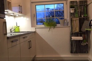 A kitchen with a window, a plant, and kitchen utensils on the wall. - Holiday home in Cuxhaven with swimming pool (Cuxhaven)