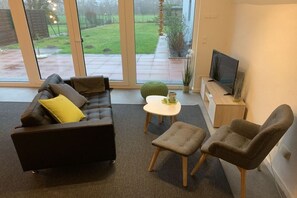 A modern living room with a sofa, two chairs, a small table, and a television. - Holiday home in Cuxhaven with swimming pool (Cuxhaven)