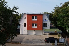 Un edificio con facciata rossa e bianca, un'area di parcheggio e un'auto nera parcheggiata davanti.