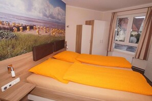 Ein Schlafzimmer mit Bett, Nachttisch, Kleiderschrank und einem Fenster mit Vorhängen.