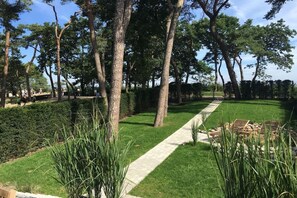 A pathway through a park-like setting with trees and manicured lawns. - Holiday home with 1 bedroom (Timmendorfer Strand)