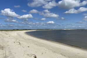 Ein Strand mit sandigem Ufer und ruhigem Wasser.