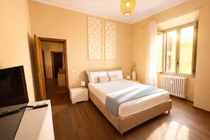 A bedroom with a bed, bedside tables, a TV, and a window with curtains. - Casa Dolce Casa Elegant Penthouse (Roma)