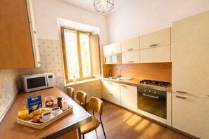 A compact kitchen with a microwave, stove, and sink. There's a breakfast tray with croissants and juice. - Casa Dolce Casa Elegant Penthouse (Roma)