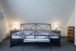A single bed with a metal frame, two bedside lamps, and a wooden dresser in a room with sloped ceilings. - Holiday home with 3 bedrooms (Dornumersiel-Westeraccumersiel)
