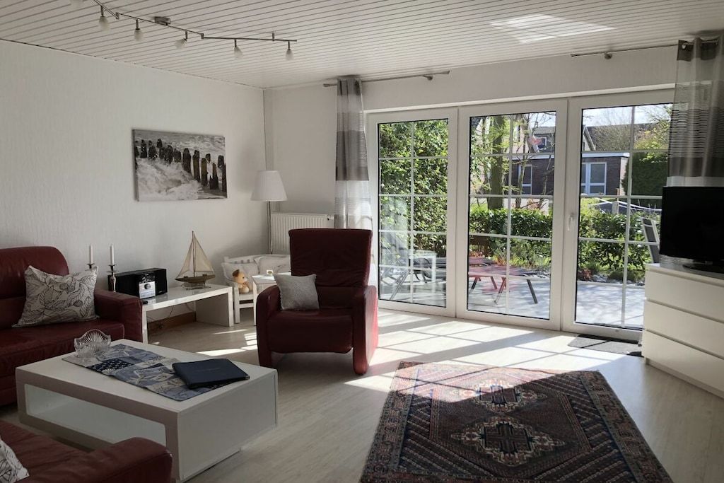 Een moderne woonkamer met een bank, fauteuil, salontafel en een groot raam met uitzicht op de omgeving.