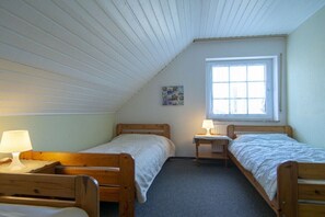 Eine kleine, einfache Unterkunft mit zwei Holzbettgestellen, einem Fenster und einer Heizung.