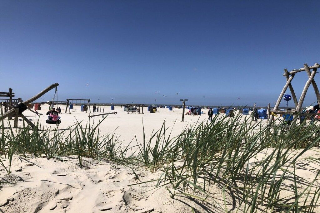 Une plage de sable avec une balançoire et une structure en bois.