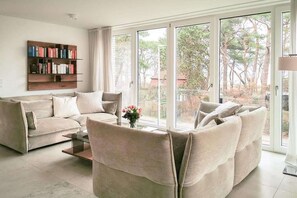 Ein Wohnzimmer mit einem beigefarbenen Sofagarnitur, einem Couchtisch und einem Bücherregal.