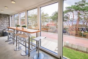 A modern kitchen with a large window, a wooden table, and bar stools. - Holiday apartment with 3 bedrooms (Timmendorfer Strand)