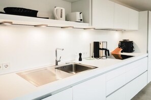 A modern kitchen with white cabinetry, stainless steel appliances, and a built-in oven. - Holiday apartment with 3 bedrooms (Timmendorfer Strand)