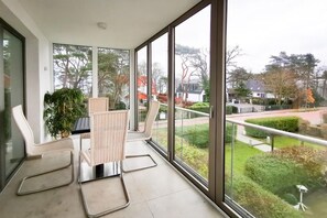 A balcony with two chairs and a table, overlooking a residential area with houses and trees. - Holiday apartment with 3 bedrooms (Timmendorfer Strand)