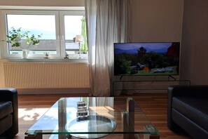 A living room with a glass coffee table, a television, and two leather sofas. - Holiday apartment with 2 bedrooms (Hameln)