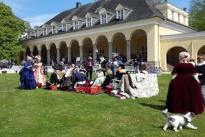 Ein historisches Gebäude mit einem überdachten Innenhof, Außenbestuhlung und Personen in historischen Kostümen.