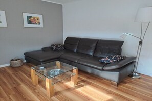 Ein modernes Wohnzimmer mit einer Ledersofa, einem Glastisch und einer Stehlampe.