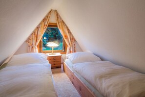 A small, cozy room with two beds, a nightstand, and a window with curtains. - Wangels (Swedish House) (Wangels)