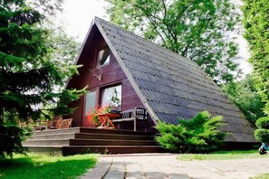 A house with a sloped roof, a porch with wooden chairs, and a stone pathway leading to the entrance. - Wangels (Swedish House) (Wangels)