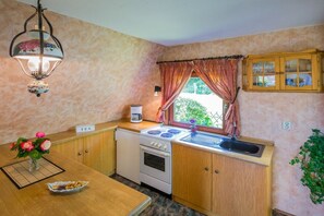 Una cuina petita amb fogó, rentapelats i finestra amb cortines.