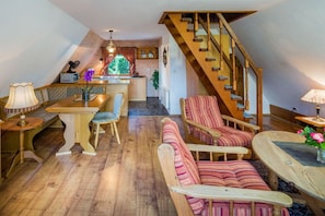 A cozy interior with a wooden staircase, a dining area with a table and chairs, and a seating area with a sofa and armchairs. - Wangels (Swedish House) (Wangels)