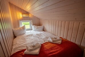 Ein Einzelbett mit weißer Bettwäsche und Kissen, eine rote Decke und zwei Handtücher auf dem Boden.