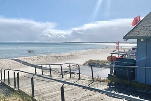 Une plage avec une promenade en bois menant à un bâtiment sur lequel flotte un drapeau.