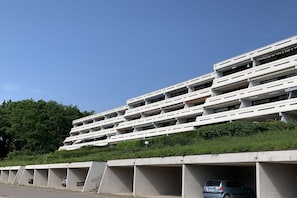 Ein modernes Gebäude mit mehreren Balkonen und einem Parkplatz mit Autos.