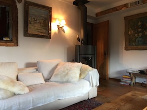 A living room with a sofa, a fireplace, and wall-mounted lighting. - Right in the Heart of Megève: Comfortable Apartment (Megève)
