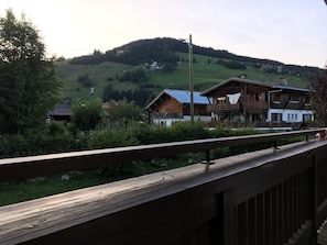 A wooden balcony overlooking a mountainous landscape with traditional chalet-style buildings. - Right in the Heart of Megève: Comfortable Apartment (Megève)