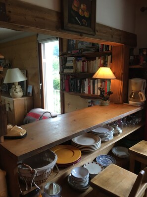 A rustic kitchen with wooden shelves, a coffee maker, and a variety of dishes and utensils. - Right in the Heart of Megève: Comfortable Apartment (Megève)