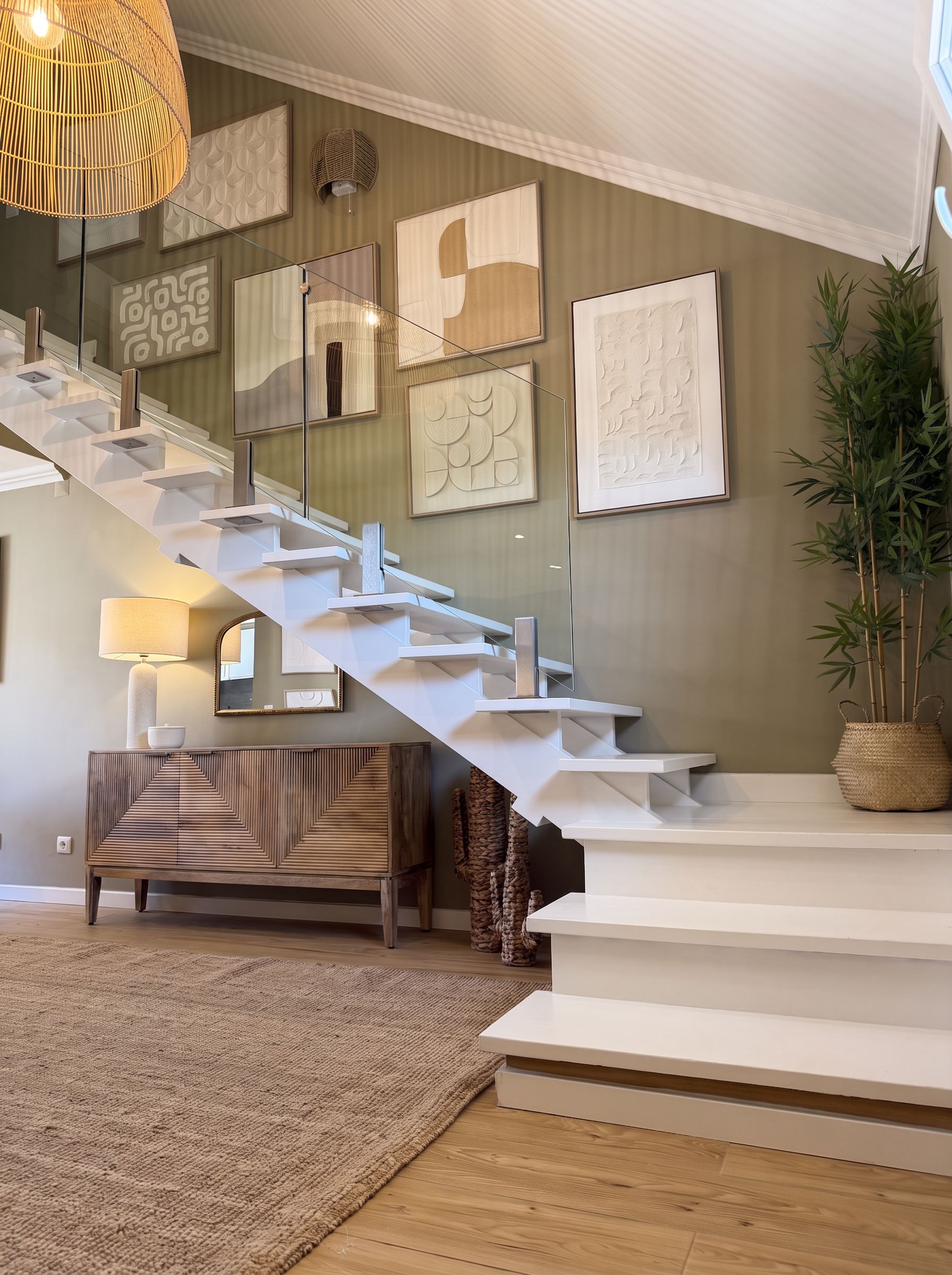 Un intérieur moderne agrémenté d’un escalier, d’œuvres d’art murales et d’une plante.