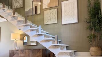 Un intérieur moderne agrémenté d’un escalier, d’œuvres d’art murales et d’une plante.