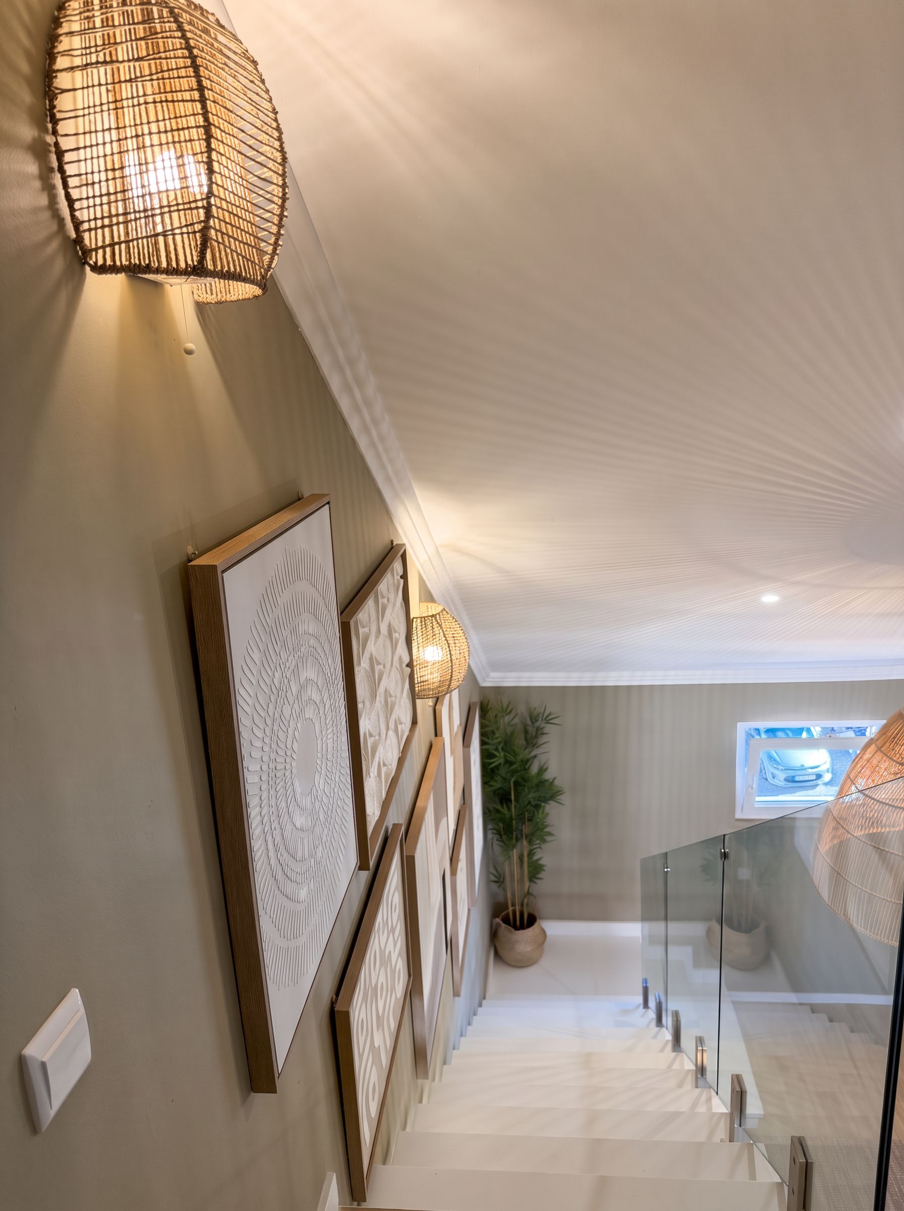 A staircase with a glass railing leading to a landing with a potted plant.